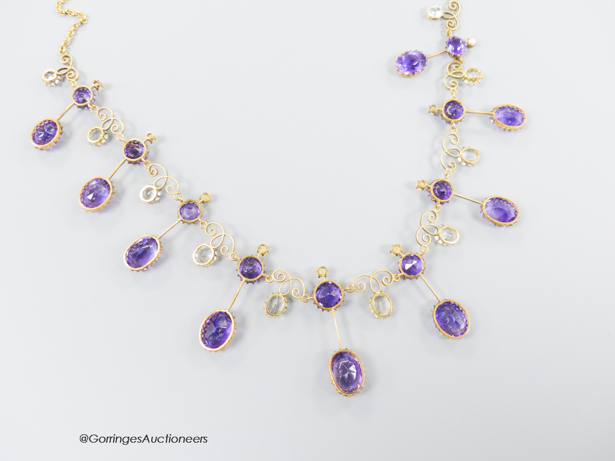 An early 20th century yellow metal, amethyst, aquamarine and seed pearl set drop fringe necklace, with later 375 clasp, 46cm, gross weight 18.6 grams.